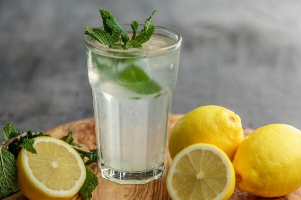 ernährung bei hitze, Glas Wasser mit Zitrone und Minze auf einem Tisch