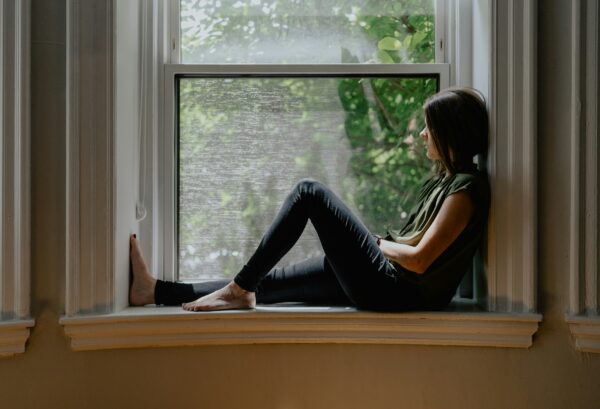 Nachdenkliche Frau sitzt am Fenster und blickt ins Freie
