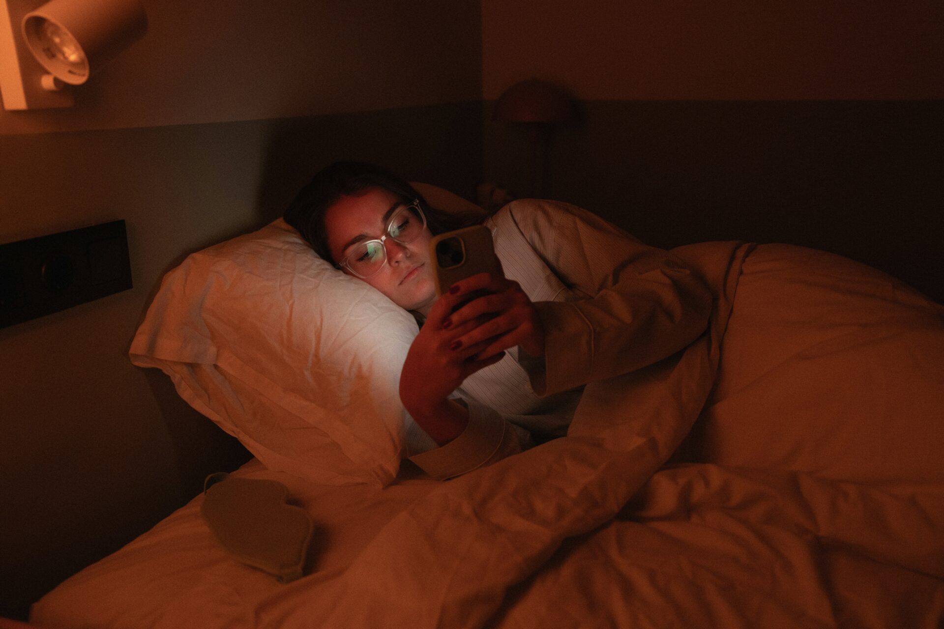 Frau schaut nachts im Bett auf ihr Smartphone und scrollt durch Social Media