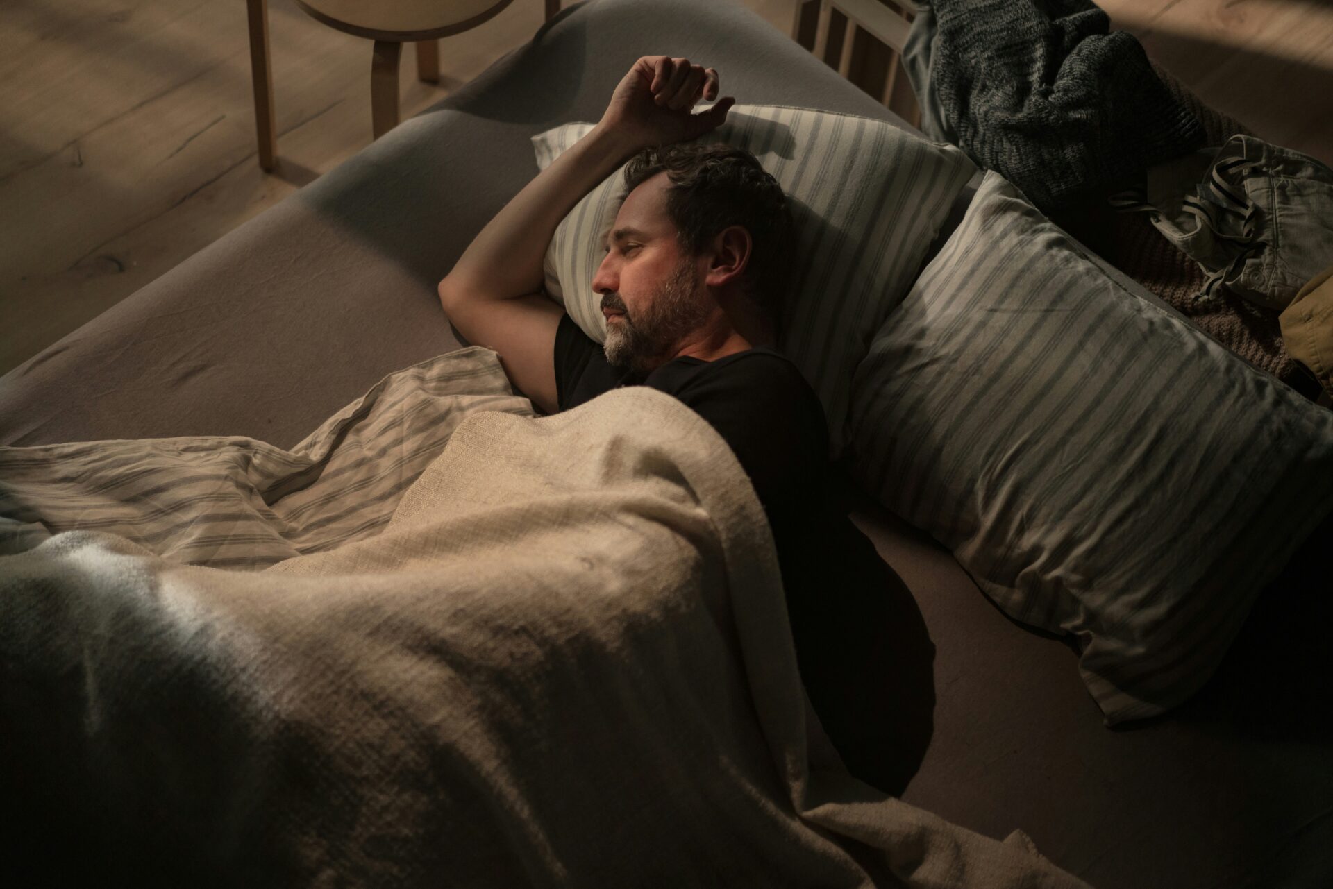 gesunder Schlaf, Mann schläft ruhig in einem dunklen Schlafzimmer