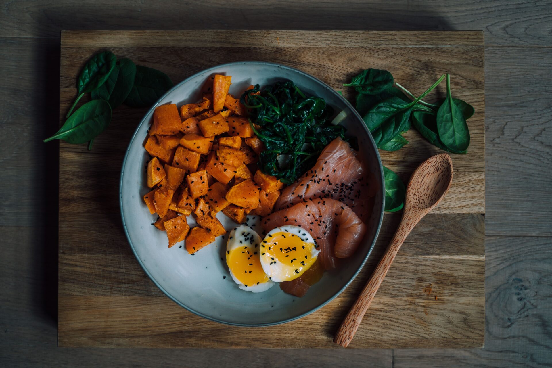 Mahlzeit mit Lachs, Ei, Spinat und Süsskartoffeln als Proteinquelle