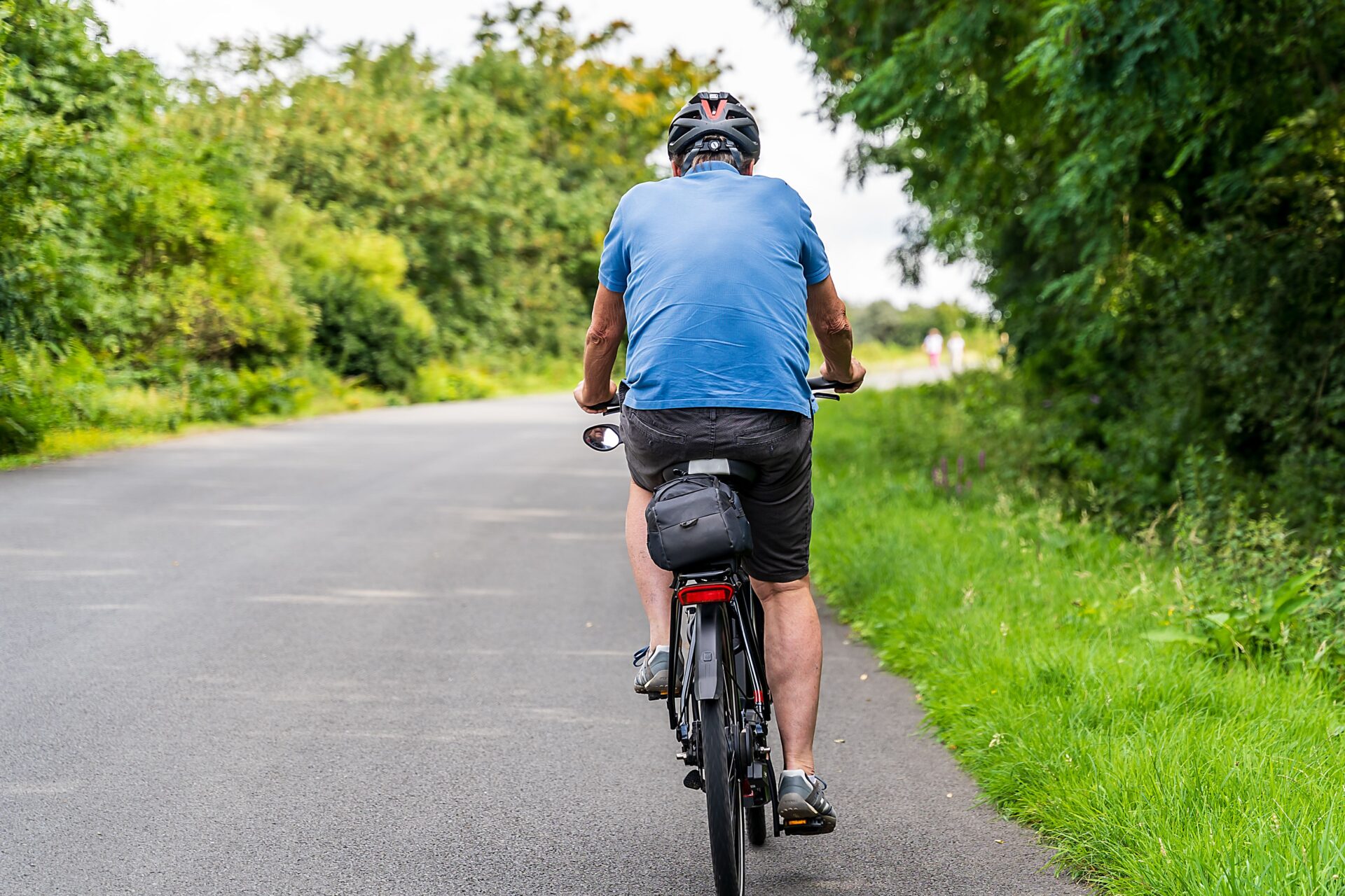 Älterer Mann fährt mit dem Fahrrad auf einer ruhigen Strasse
