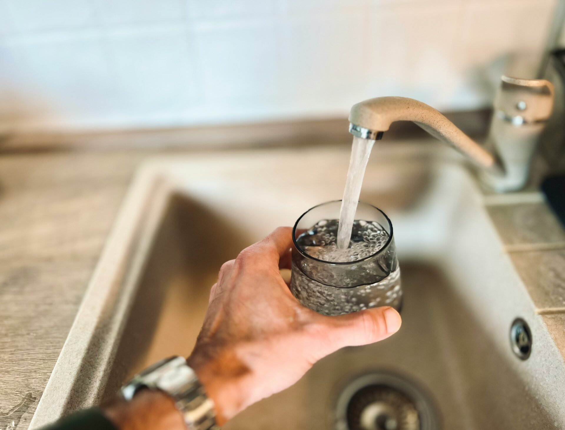 Trinkwasser wird aus einem Wasserhahn in ein Glas gefüllt