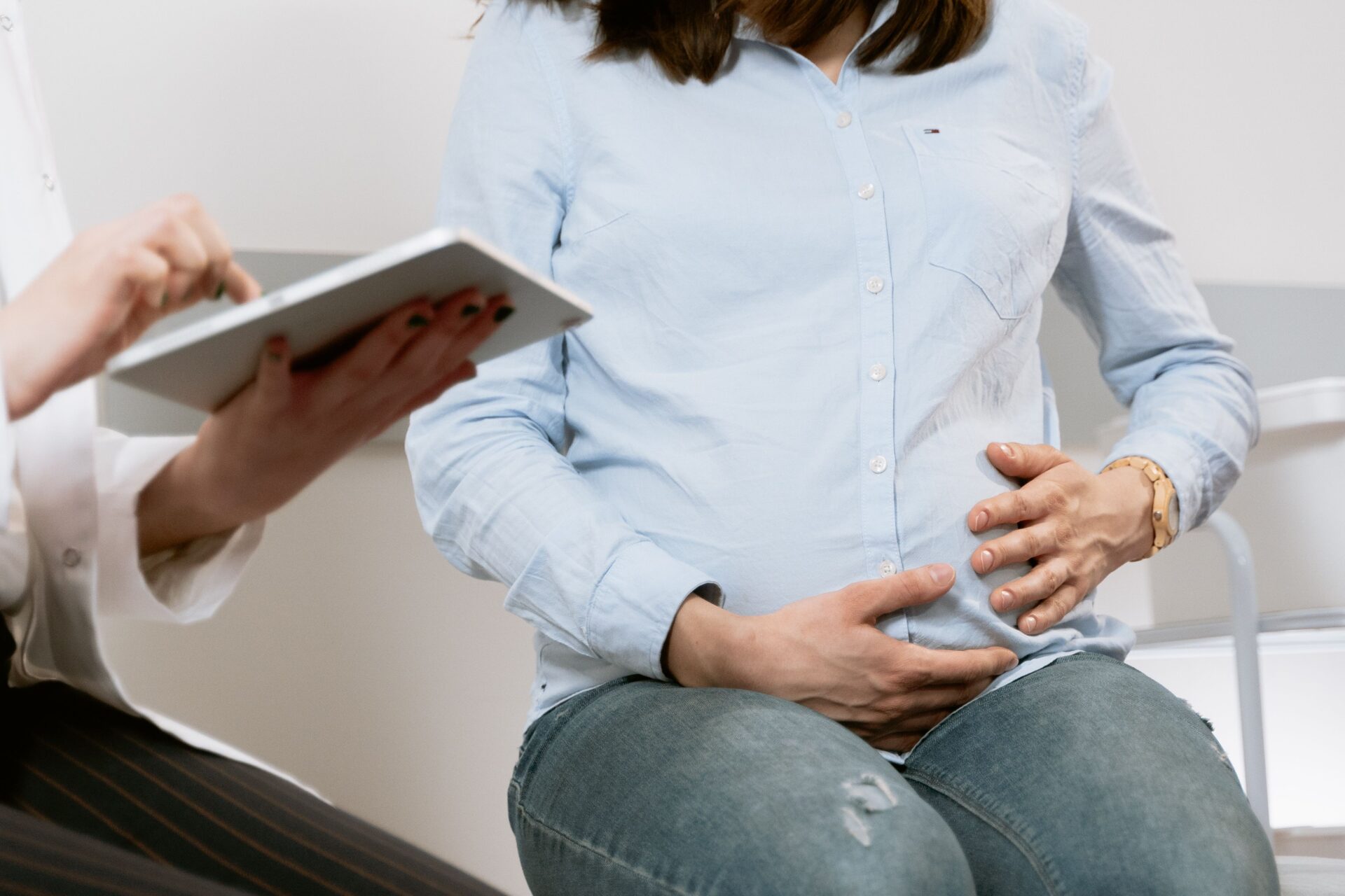 Schwangere Frau im Gespräch mit einer Fachperson, die ein Tablet hält