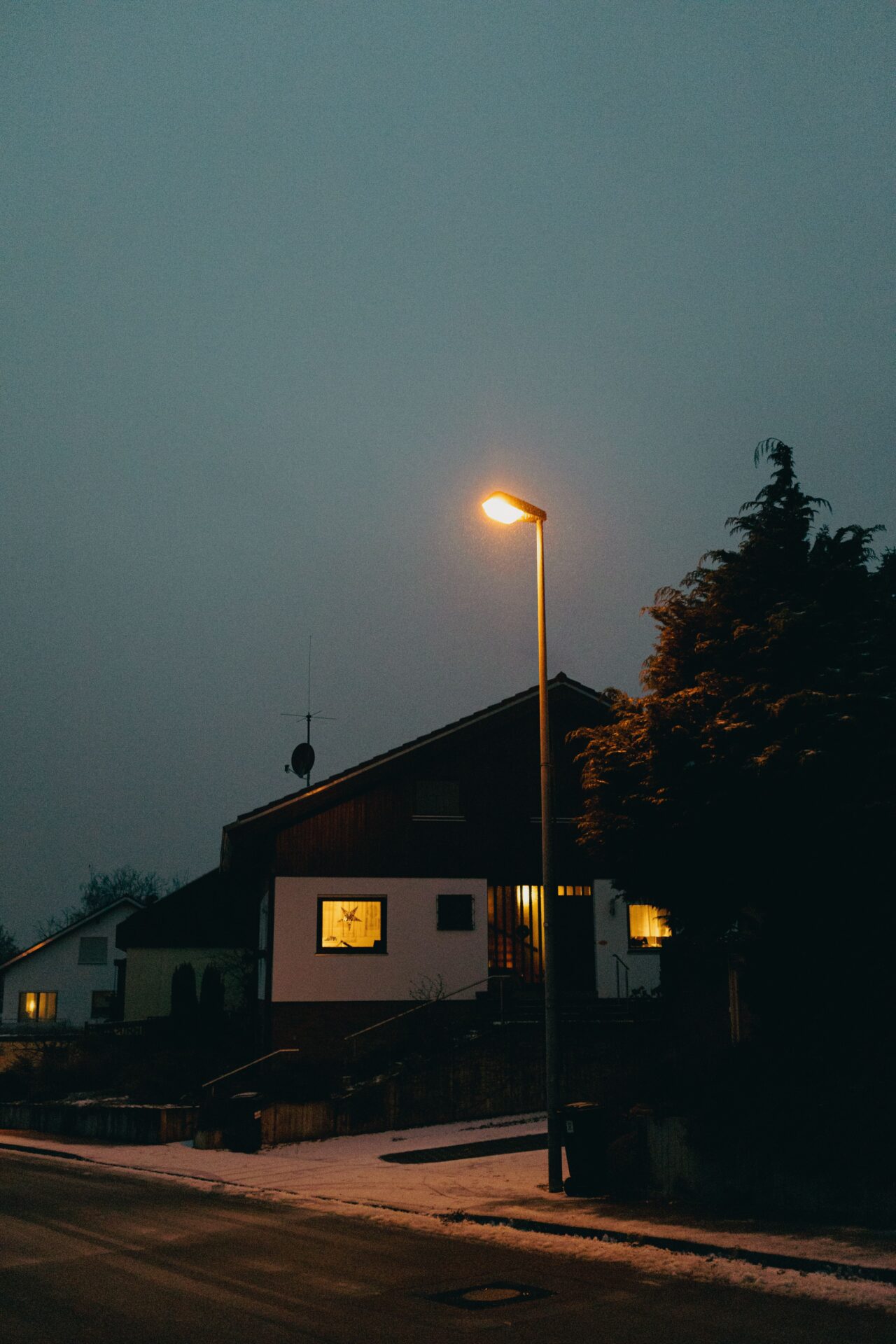 Leuchtende Strassenlaterne vor einem Wohnhaus bei Nacht